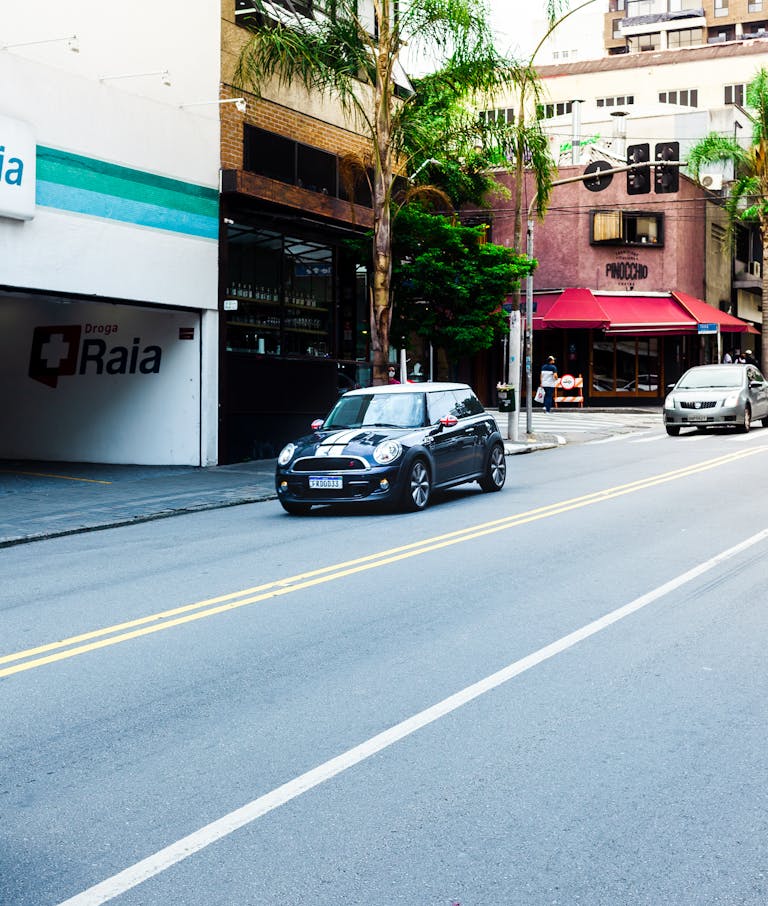 A city street with moving cars and storefronts, showcasing urban life.