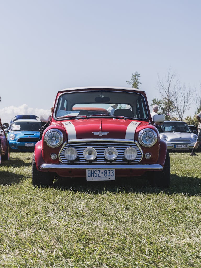 Vintage red Mini Cooper on display at an outdoor car show, capturing automotive nostalgia.